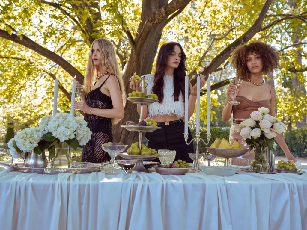 Three models with long, glossy hair at an outdoor table
