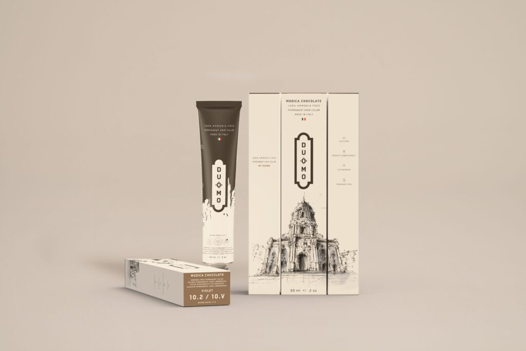 Duomo 10.2 / 10V - Modica Chocolate - Violet hair color tube and boxes on a beige backdrop