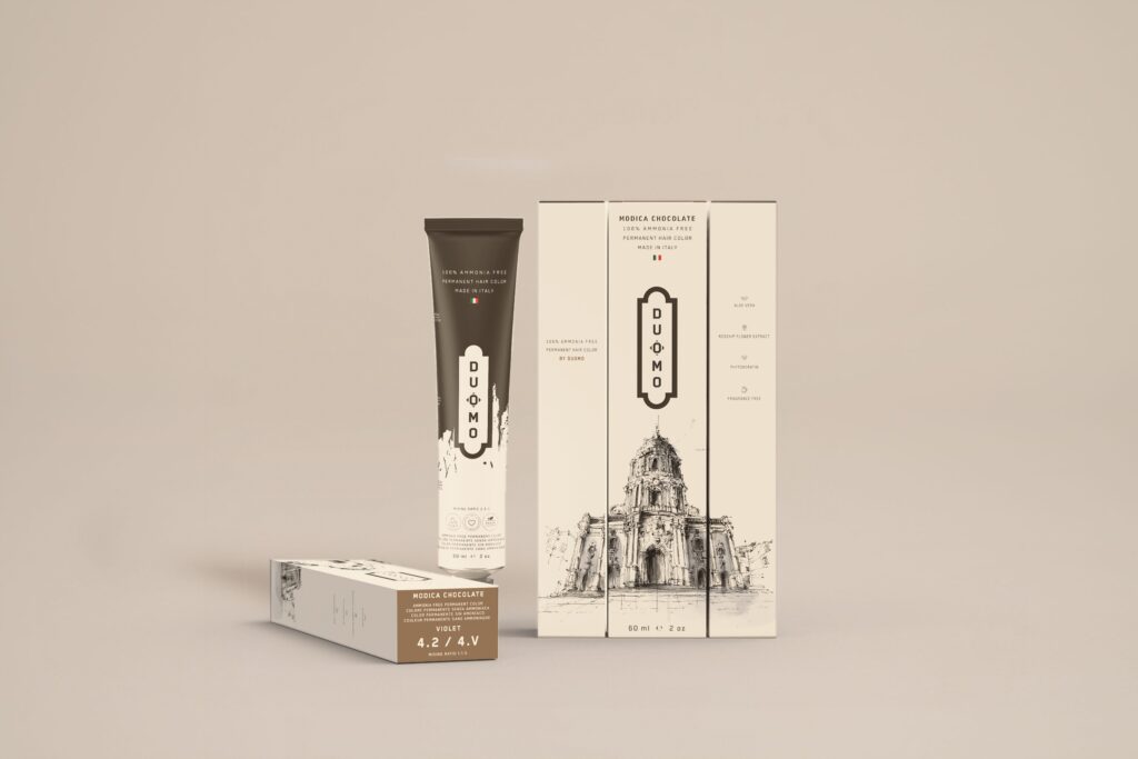 Duomo 4.2 / 4V - Modica Chocolate Violet hair color tube and boxes on a beige backdrop
