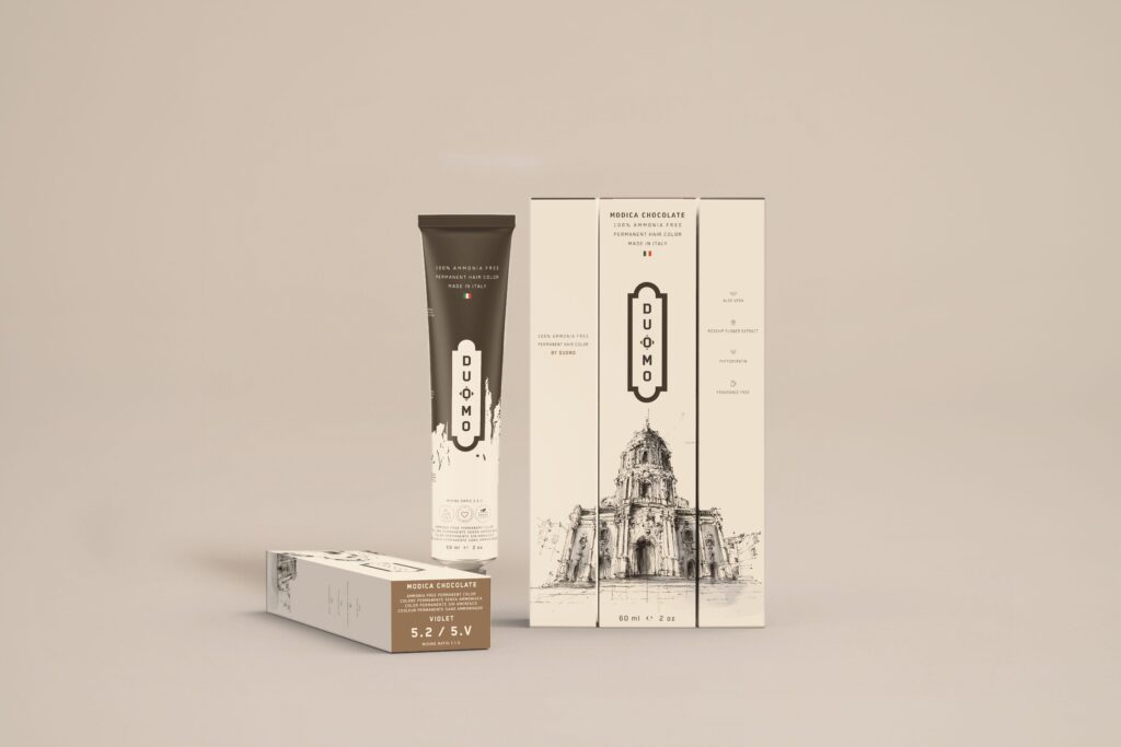 Duomo 5.2 / 5V - Modica Chocolate Violet hair color tube and boxes on a beige backdrop