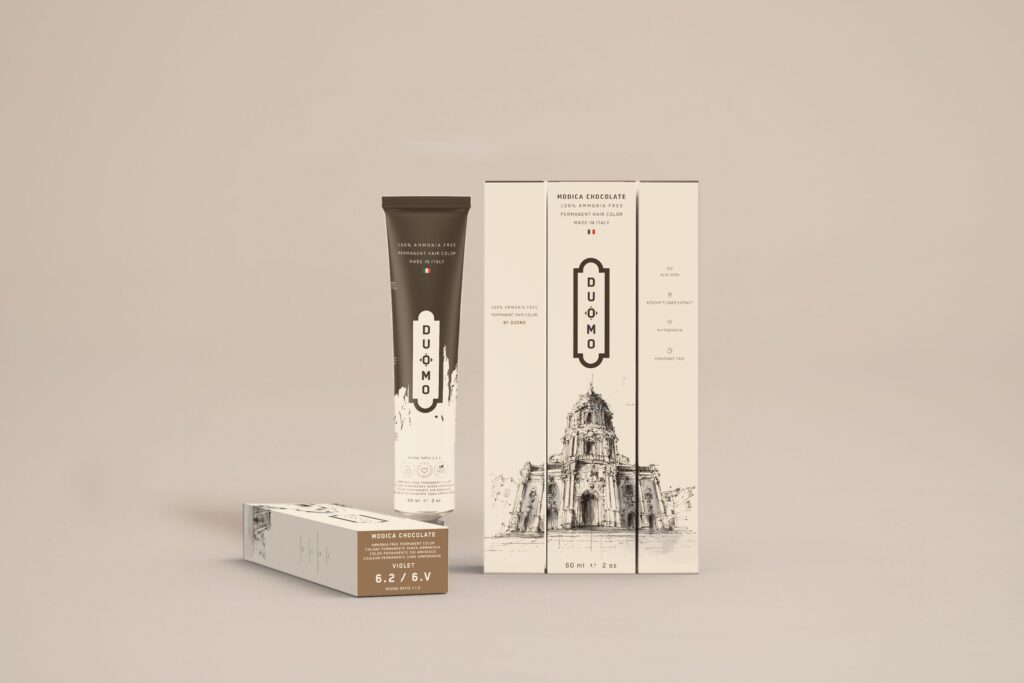 Duomo 6.2 / 6V - Modica Chocolate Violet hair color tube and boxes on a beige backdrop